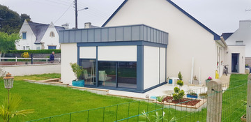 Cette extension à toiture plate et acrotère zinc est résolument moderne et s'insère parfaitement sur une maison récente